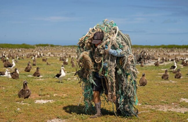 Photo: A team member of the Papahānaumokuākea Marine Debris Project carries a massive ball of fishing gear
