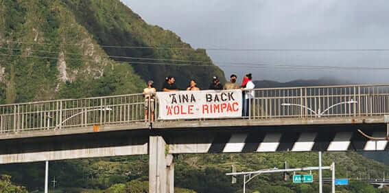 Photo: Members of Hui Aloha ʻĀina o Koʻolaupoko hold a banner protesting RIMPAC on an overpass in Kāneʻohe