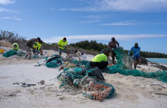 Photo: Technicians remove fishing nets from the shores of Kuaihelani