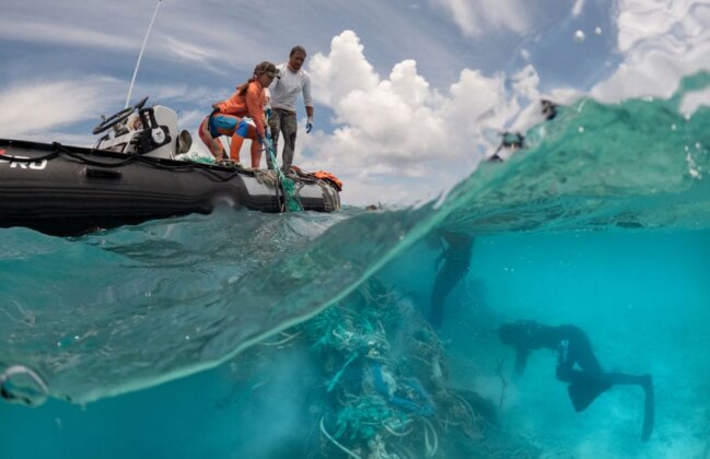 Photo: Divers gather fishing nets from the reef