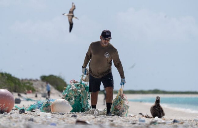 Photo: NOAA team member pulls fishing nets across the beach