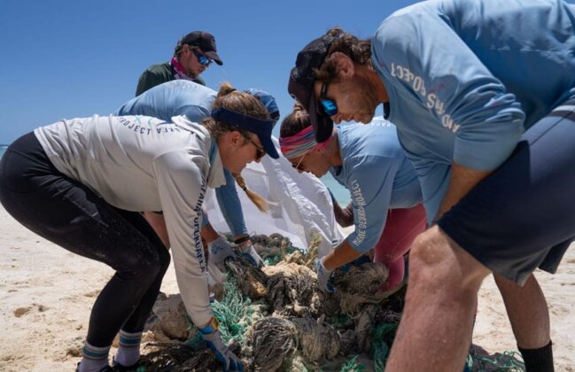 Photo: NOAA team members gather fishing nets on the beach