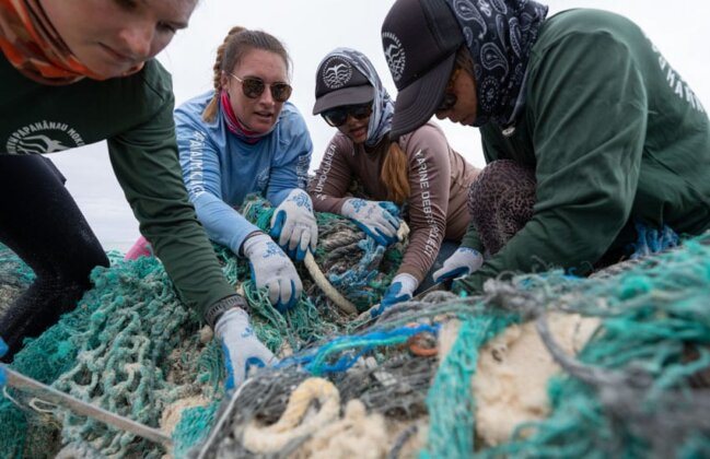 Photo: NOAA team members gather fishing nets on the beach