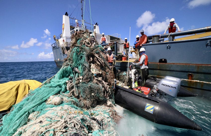Photo: Technicians remove a fishing net from the shores of Kuaihelani